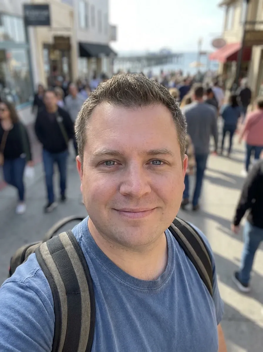 Original selfie input — man in a blue T-shirt in an outdoor crowd